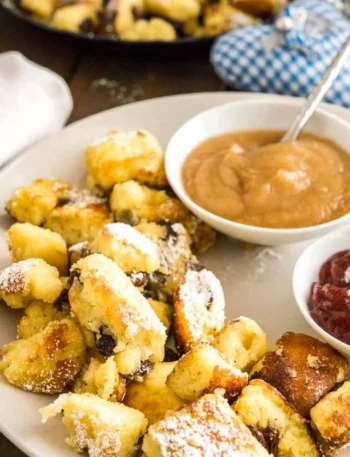 Original Kaiserschmarrn Rezept mit Rosinen und Apfelmus auf weißem Teller serviert