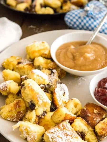 Original Kaiserschmarrn Rezept mit Rosinen und Apfelmus auf weißem Teller serviert