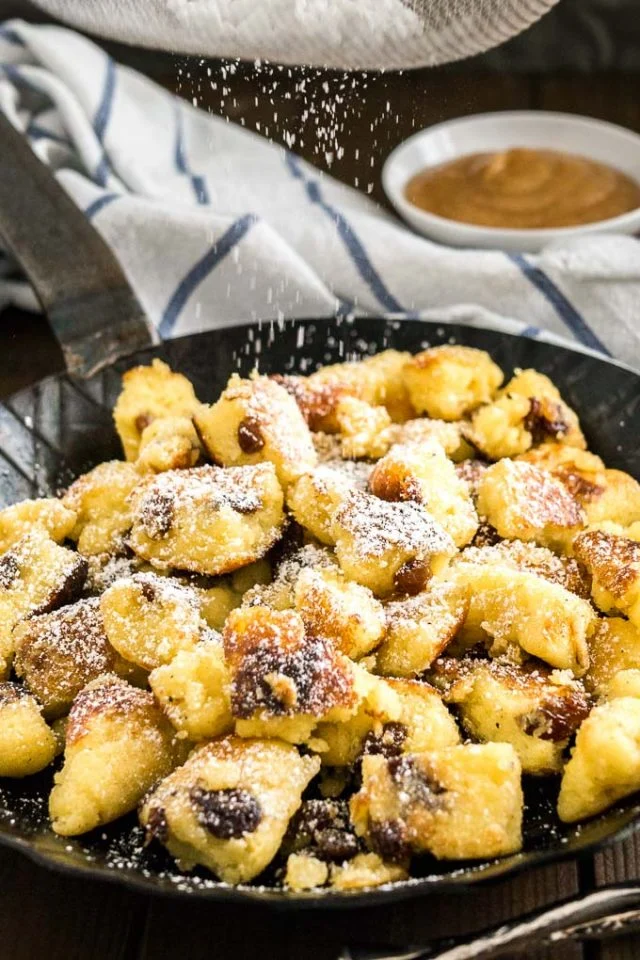 Original Kaiserschmarrn Rezept mit Rosinen und Apfelmus frisch in der Pfanne mit Puderzucker bestäubt