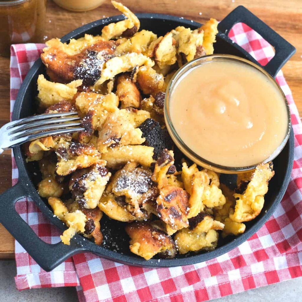 Original Kaiserschmarrn Rezept mit Rosinen und Apfelmus in der Pfanne angerichtet
