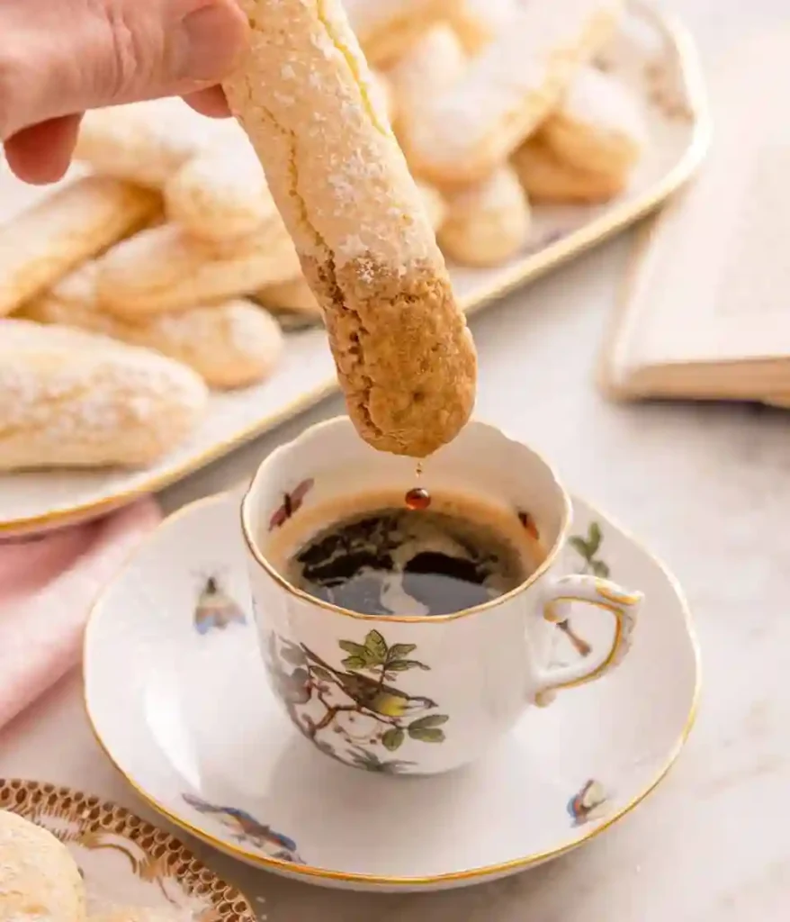 Löffelbiskuit wird in eine Tasse Kaffee getaucht – ideal zum Servieren