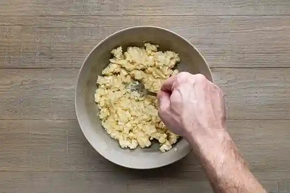 Zubereitungsschritt im rezept für obazda – Camembert wird mit einer Gabel zerdrückt