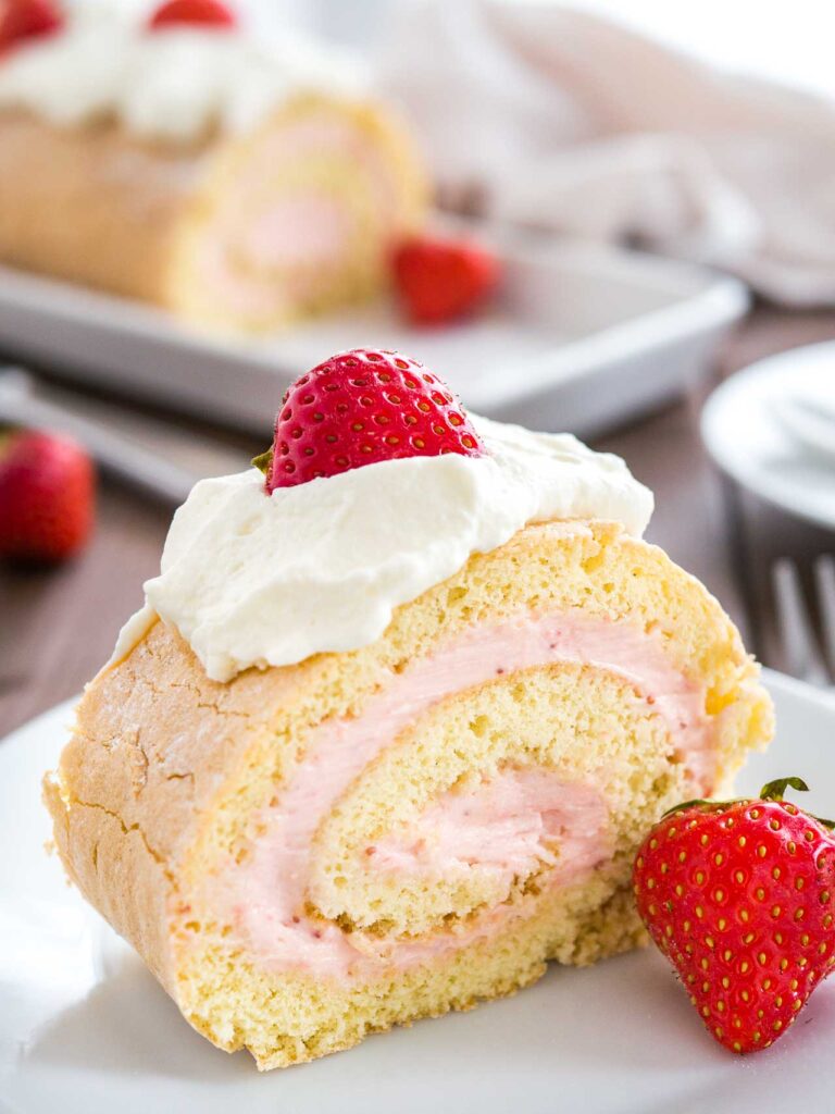Biskuitrolle mit Erdbeeren und Erdbeer-Sahne-Füllung – angeschnitten serviert
