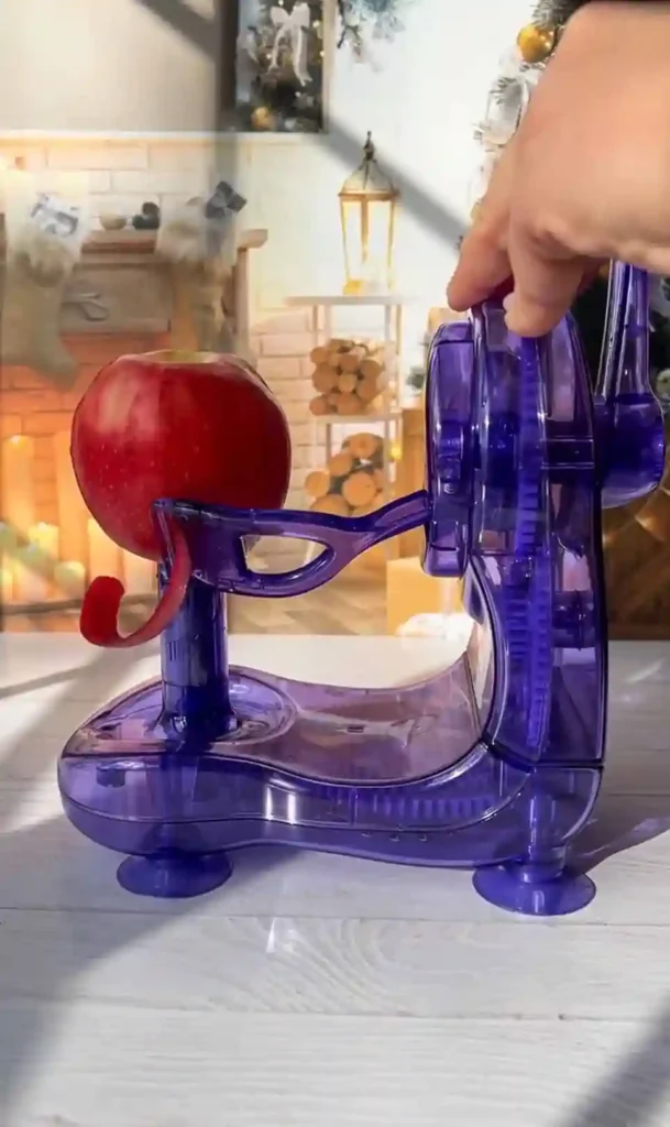 Apfelschäler im Einsatz mit rotem Apfel in moderner Küche, ideal zum Schälen für französischen Apfelkuchen.