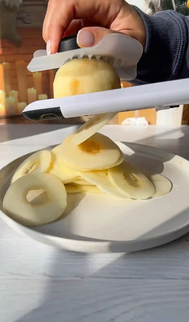 Apfel wird mit Mandoline in dünne Ringe geschnitten – perfekt für französischen unsichtbaren Apfelkuchen.