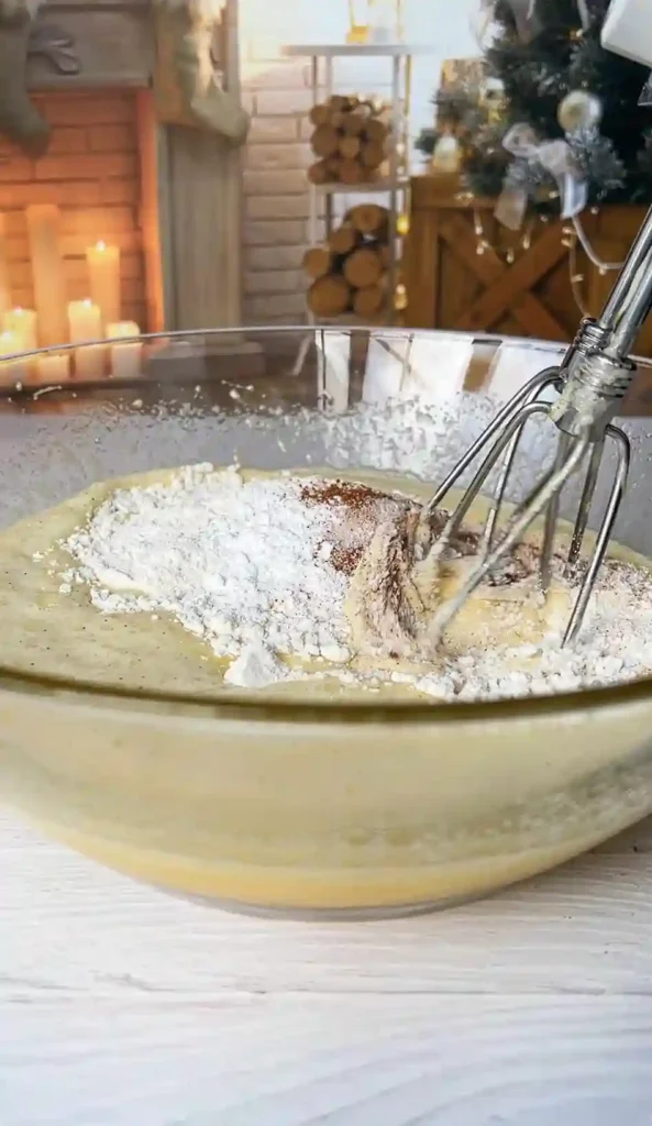Teig für französischer unsichtbarer Apfelkuchen wird mit Handmixer glatt gerührt – Mehl, Zimt, Backpulver und Salz werden vermengt.