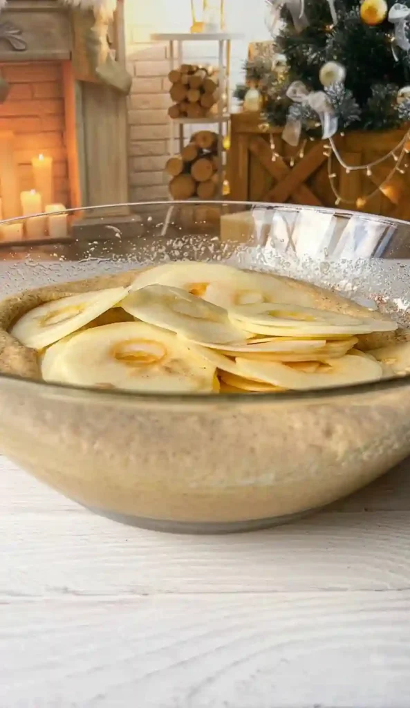 Dünn geschnittene Apfelscheiben im Teig für französischer unsichtbarer Apfelkuchen.