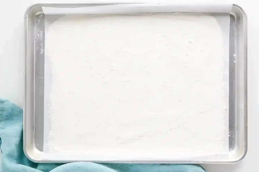 Backblech mit ausgebreitetem Mehl zur Hitzebehandlung für essbaren Cookie Dough Teig ohne Ei.