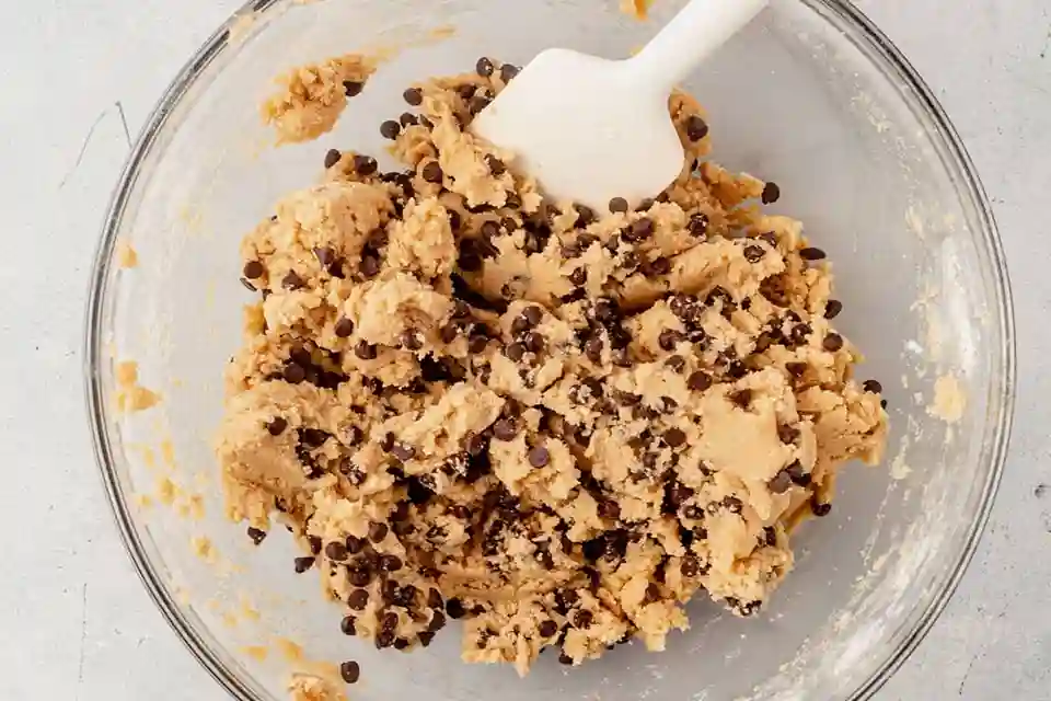Frischer Keksteig zum Löffeln mit Schokodrops – perfekter cookie dough rezept Moment in einer Glasschüssel.