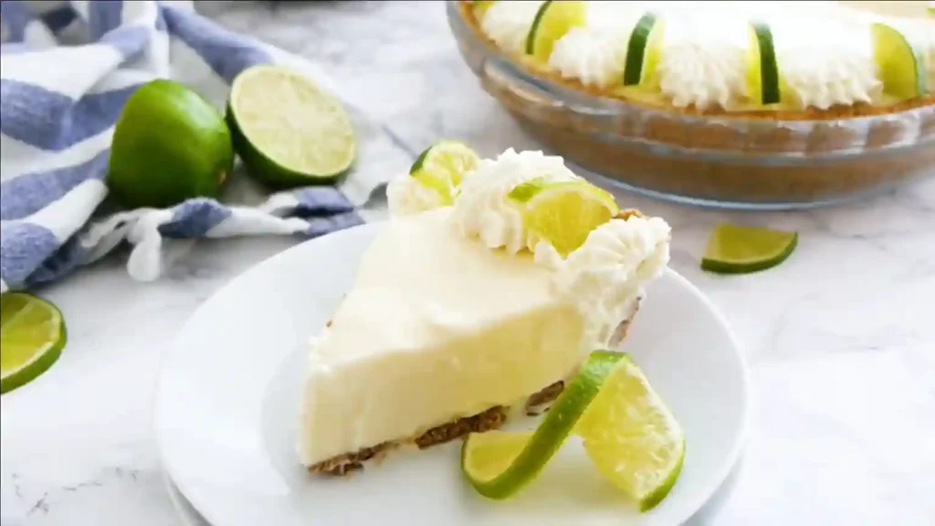 Ein Stück aus dem No Bake Key Lime Pie Rezept, dekoriert mit Sahne und frischen Limetten