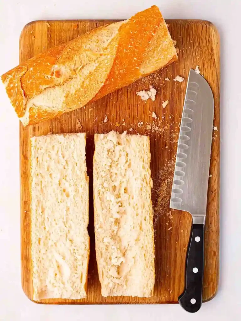 Baguette halbiert für Pizza Baguette Rezept auf Holzbrett mit Messer