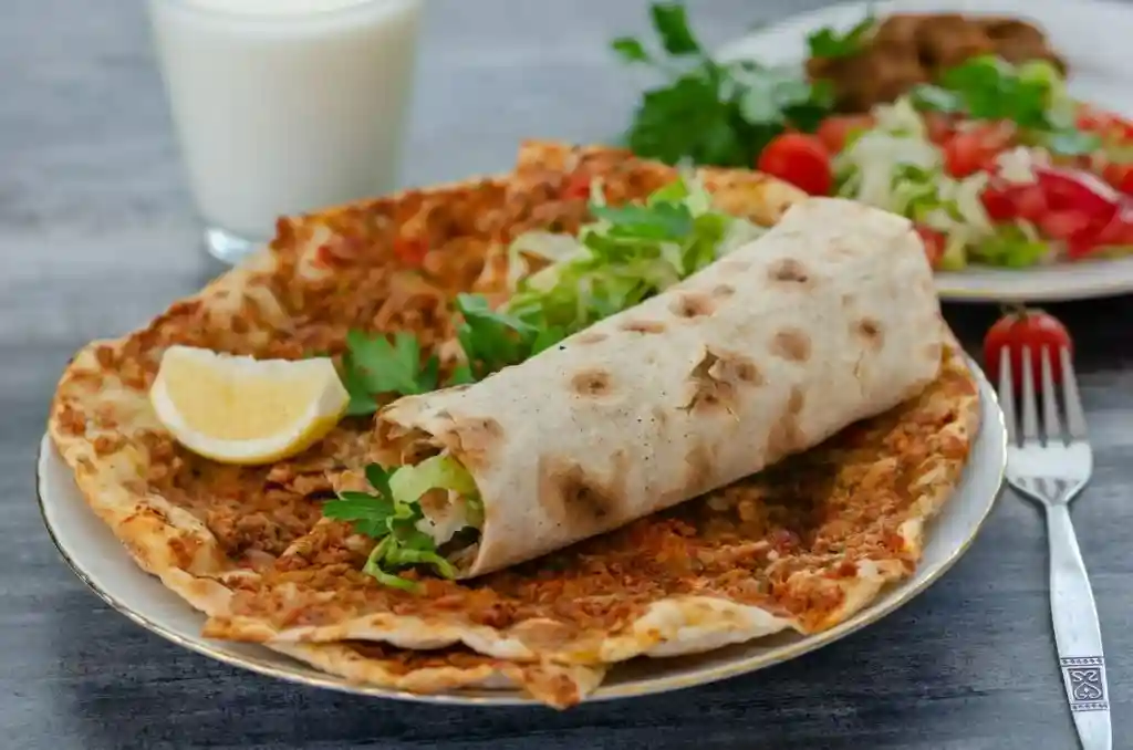 Lahmacun selber machen – türkische Pizza Rezept auf dem Teller mit Hackfleischbelag, gerolltem Fladenbrot, Salat und Zitronenspalte