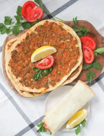 Frisch gebackene Lahmacun Turkish Pizza mit Zitronenspalten, Petersilie und Tomaten – perfekt zum Lahmacun selber machen.