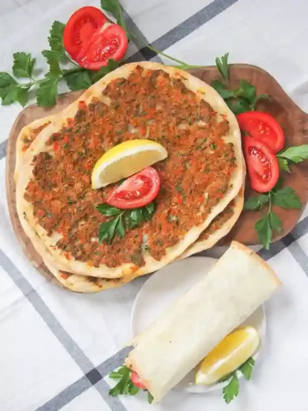 Frisch gebackene Lahmacun Turkish Pizza mit Zitronenspalten, Petersilie und Tomaten – perfekt zum Lahmacun selber machen.