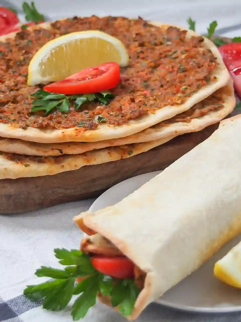 Gerollter Lahmacun mit Petersilie und Tomate – türkische Pizza zum selber machen, serviert mit Zitrone.