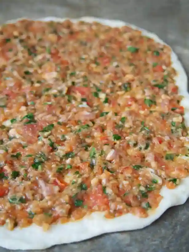Ungebackener Lahmacun mit frischer Füllung – türkische Pizza vor dem Backen mit Hackfleisch, Tomaten und Petersilie.