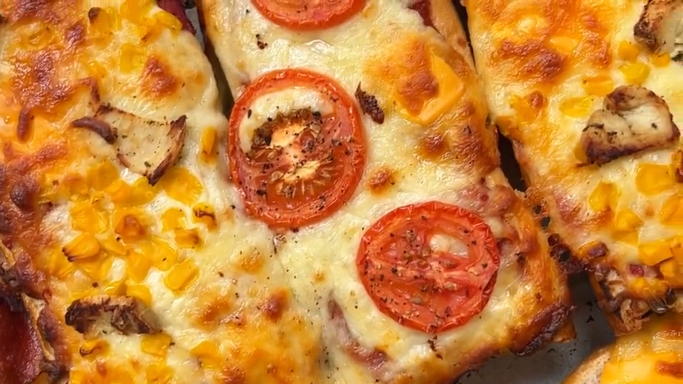 Frisch gebackenes Pizza Baguette mit Tomaten, Käse, Mais und Hähnchen