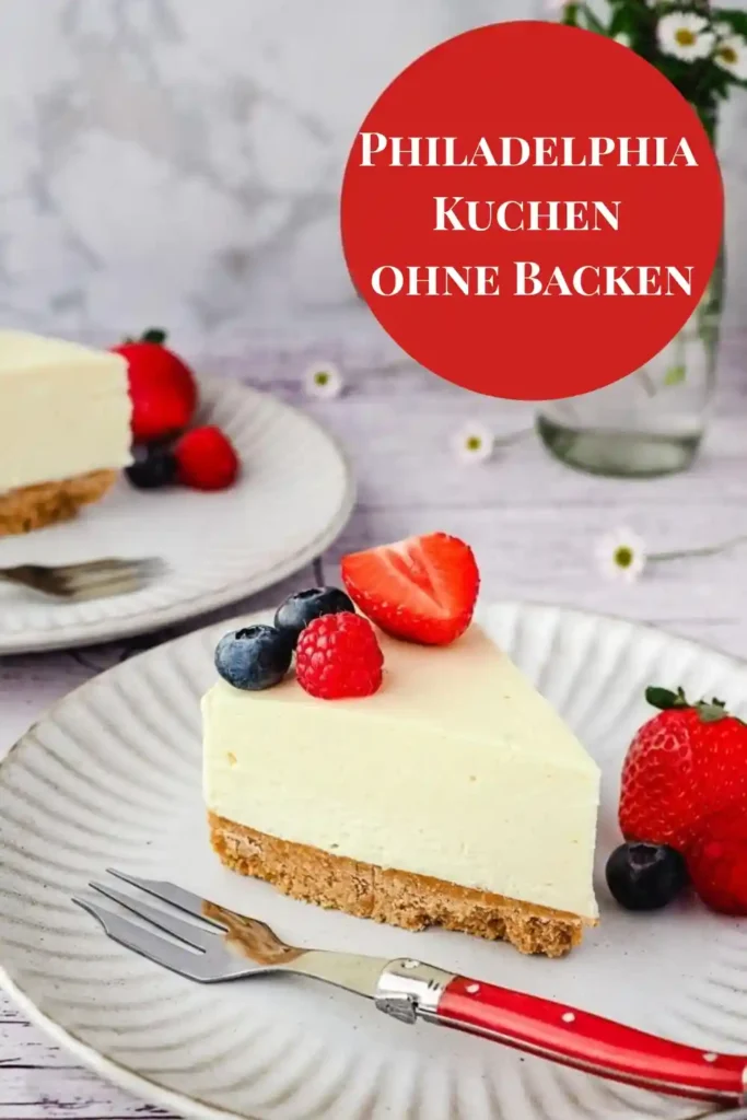 Stück Philadelphia Kuchen ohne Backen mit Keksboden und Beeren auf einem Teller, dekoriert mit Erdbeeren, Himbeeren und Blaubeeren