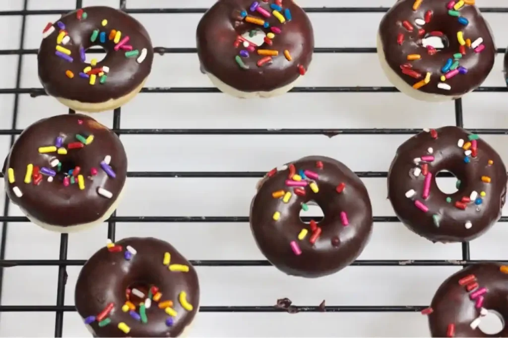 Mini Donuts mit Schokoglasur und bunten Streuseln auf Gitter – donuts rezept backofen silikonform