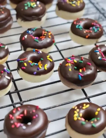 Mini Donuts im Backofen mit Schokoglasur und bunten Streuseln auf Gitterrost