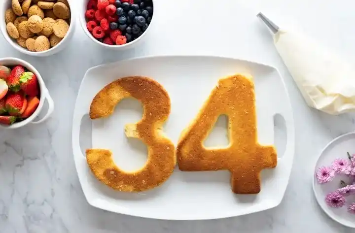 Das Bild zeigt frisch gebackene Biskuitböden, die in Ziffernform wie 3 und 4 geschnitten wurden – perfekt für eine selbstgemachte Zahlentorte ohne spezielle Backform. Mit Hilfe einer Schablone oder der Zahlentorte Vorlage als PDF lassen sich diese Zahlen einfach und präzise ausschneiden. Diese Methode eignet sich ideal für alle, die einen Geburtstagskuchen mit Zahl selber machen möchten – ganz ohne Spezialwerkzeug.