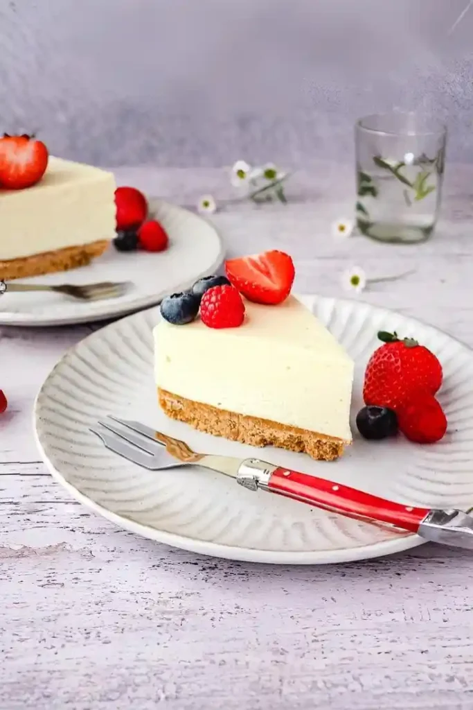 Philadelphia Kuchen ohne Backen mit Keksboden, serviert mit frischen Beeren wie Erdbeeren, Himbeeren und Blaubeeren auf einem Teller