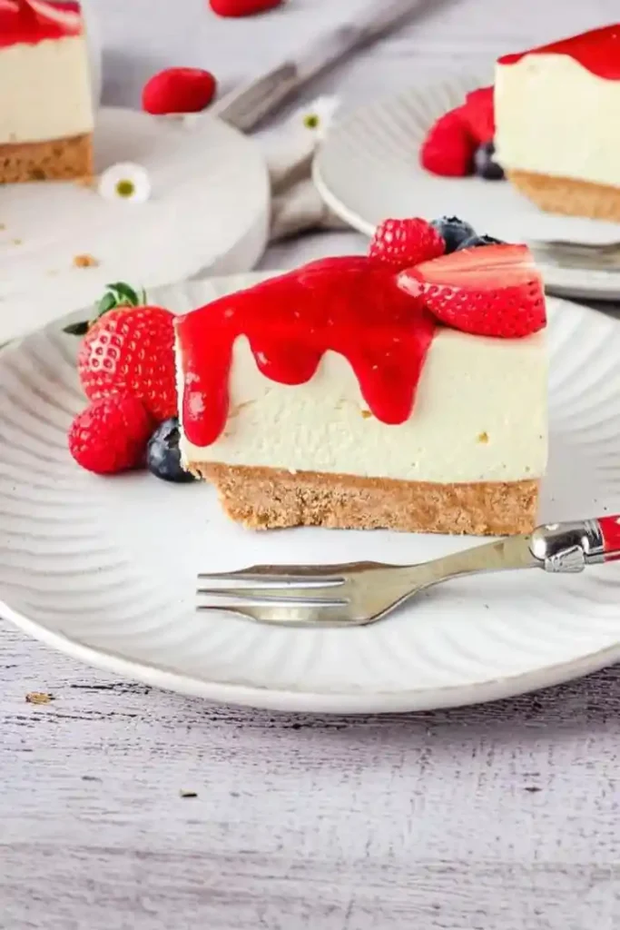 Philadelphia Frischkäsekuchen mit Erdbeersoße und frischen Beeren auf einem Teller serviert