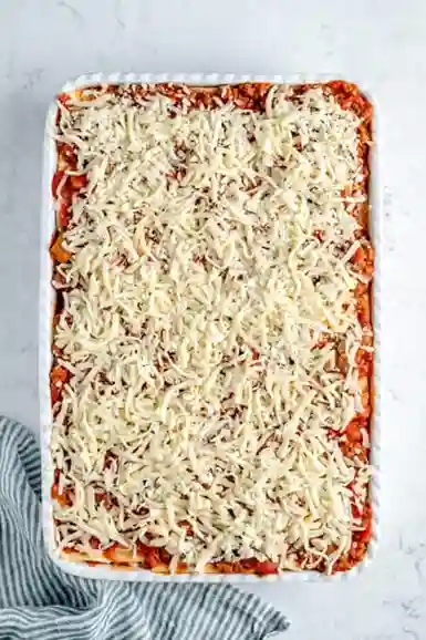 Finale Käseschicht auf veganer Lasagne vor dem Backen