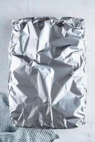 Vegane Lasagne mit Alufolie abgedeckt vor dem Backen