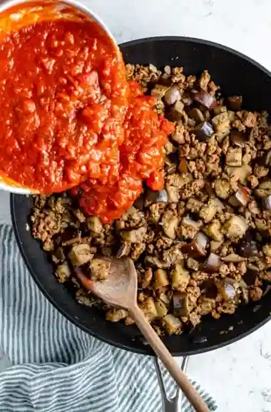 Tomatensauce wird zu veganem Hack mit Auberginen für Lasagne gegeben