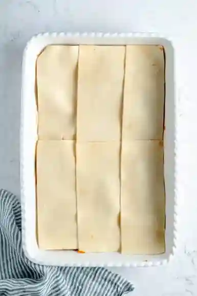 Lasagneblätter als erste Schicht in Auflaufform für vegane Lasagne