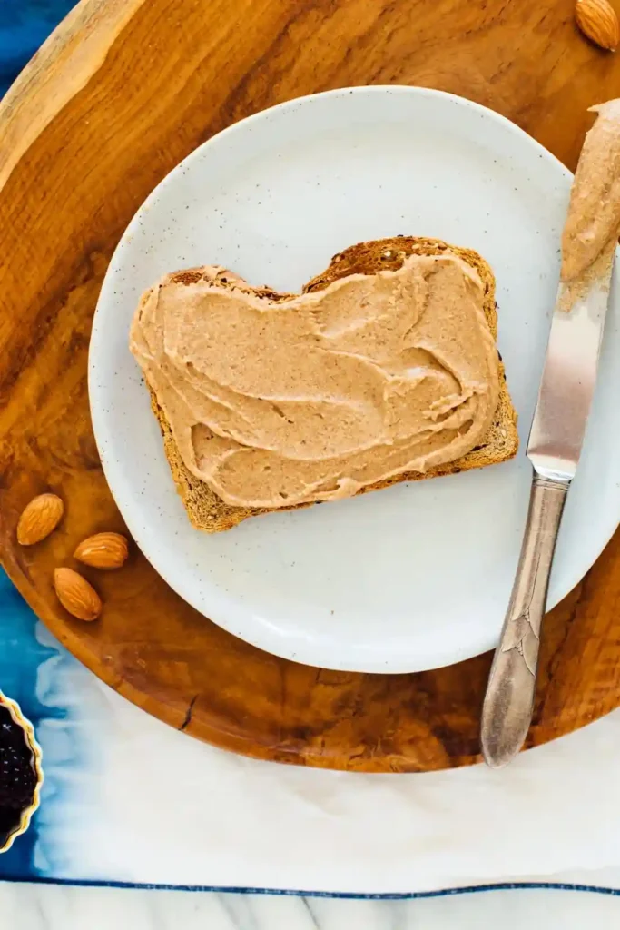 Vollkornbrot mit selbstgemachtem Mandelmus bestrichen – perfekte Mandelmus Verwendung zum Frühstück oder Snack.