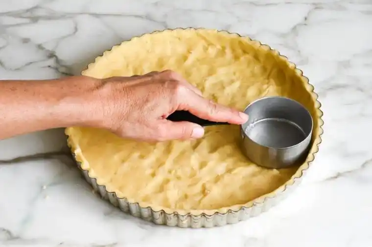 Mürbeteigboden für französische Tarte au Chocolat wird in Tarteform gedrückt