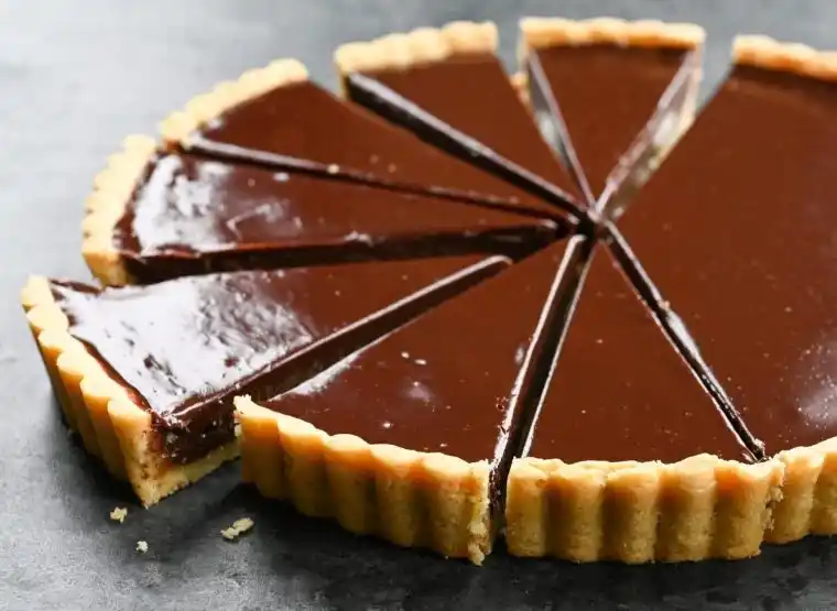 Französische Tarte au Chocolat angeschnitten in 10 Stücke mit glänzendem Schokoladenguss