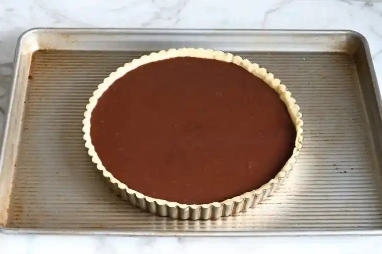 Französische Tarte au Chocolat ungebacken in Tarteform auf Backblech