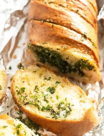 Knuspriges Kräuterbaguette mit Kräuterbutter frisch aufgeschnitten auf Alufolie – perfekt zum Selbermachen