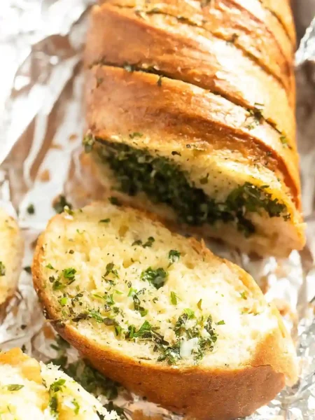 Knuspriges Kräuterbaguette mit Kräuterbutter frisch aufgeschnitten auf Alufolie – perfekt zum Selbermachen