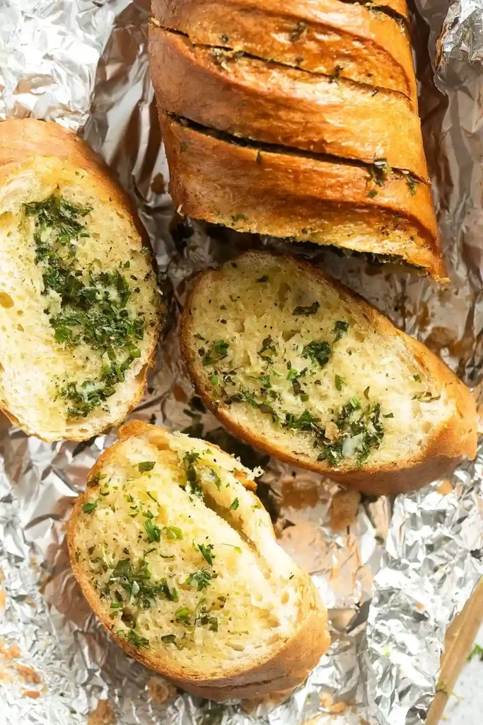 Kräuterbaguette frisch gebacken – aufgeschnitten mit aromatischer Kräuterbutterfüllung