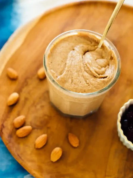 Cremiges Mandelmus selbst gemacht im Glas mit Mandeln auf Holzbrett – perfektes Mandelmus Rezept für gesunde Küche.