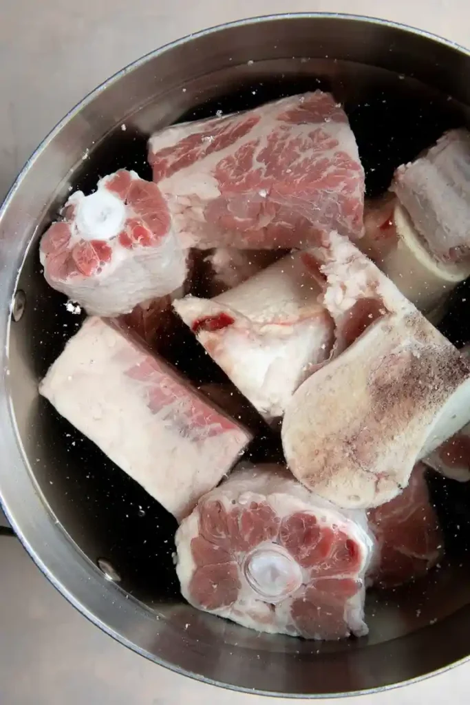 Rinderknochen im Topf mit Wasser zum Blanchieren für Knochensuppe