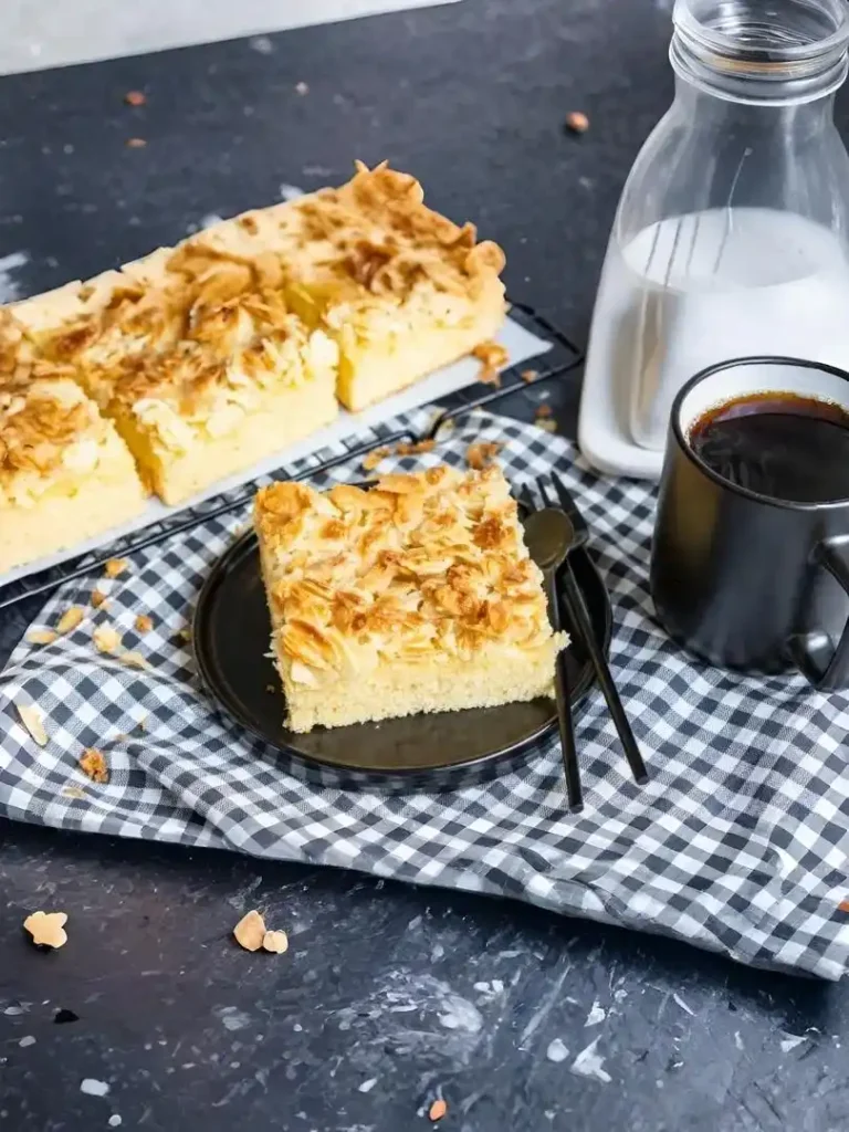 Schneller Butterkuchen ohne Hefe mit Mandeln auf schwarzem Teller serviert