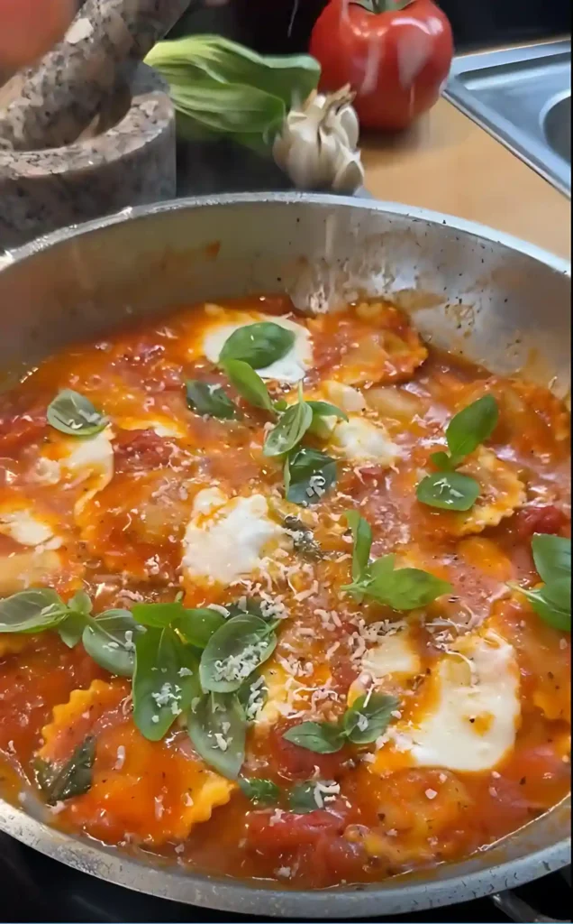 Ravioli mit Tomatensauce in der Pfanne, überzogen mit Mozzarella, frischem Basilikum und Parmesan – eine schnelle Sauce zu Ravioli.