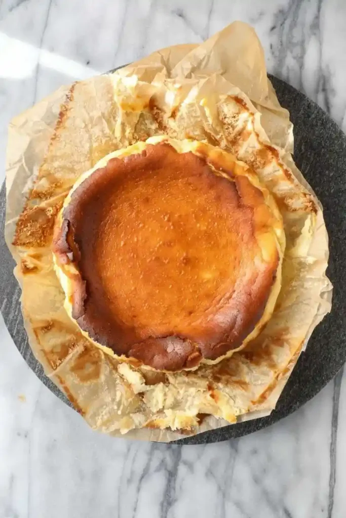 Kleiner Käsekuchen ohne Boden nach dem Backen in 18 oder 20 cm Springform mit Backpapier auf Marmorplatte