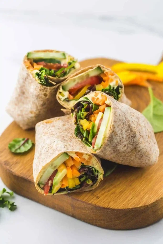 Hummus-Gemüse-Wrap als frisches essen zum mitnehmen arbeit kalt auf Holzbrett serviert.