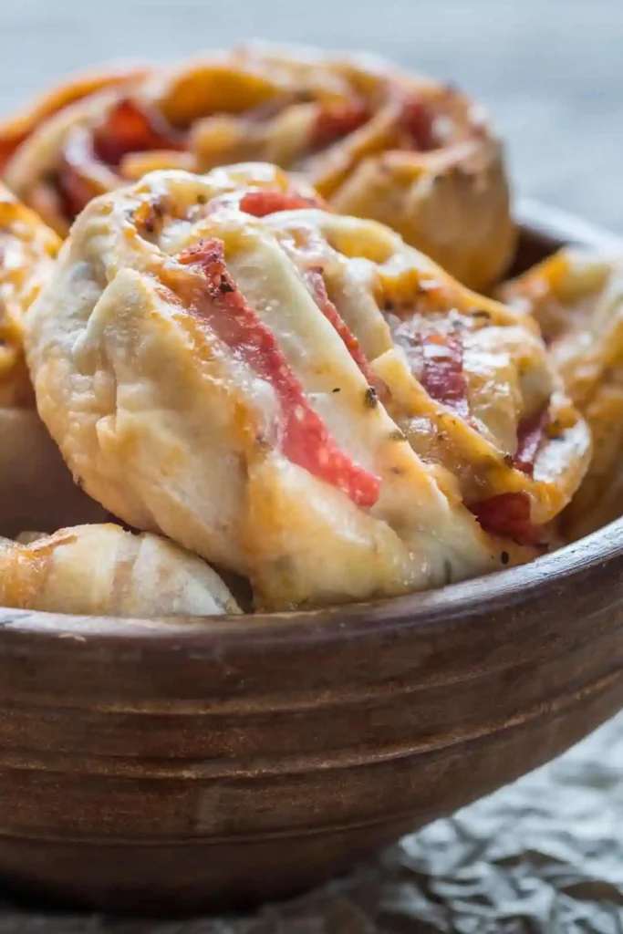 Frisch gebackene Low Carb Pizzaschnecken in einer Holzschale – gesunde Pizza Schnecken mit Käse und Salami