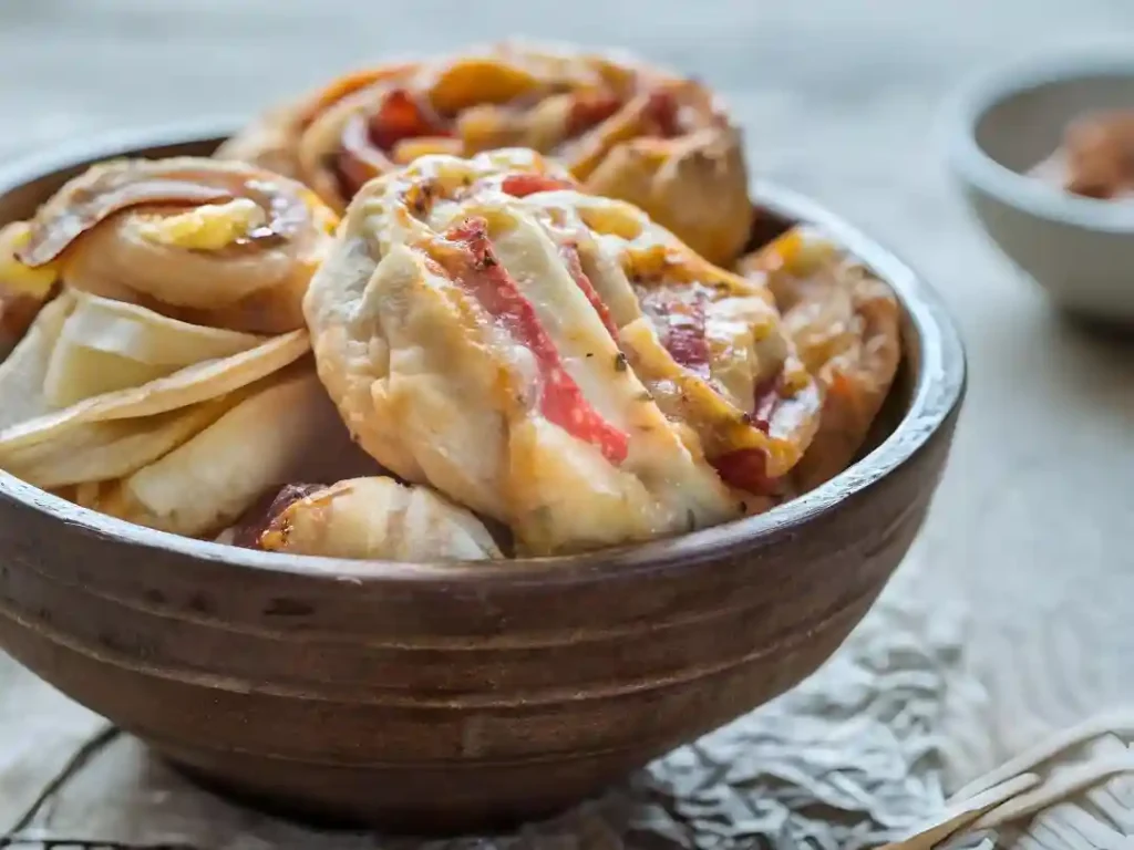 Low Carb Pizzaschnecken in Schüssel serviert – gesundes Fingerfood mit Käse und Salami