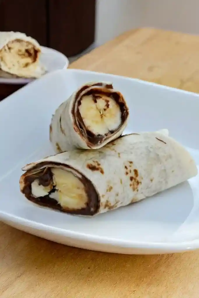 Tortilla-Röllchen mit Nutella und Banane auf einem weißen Teller – schneller süßer Snack in 5 Minuten, ideal zum Selbermachen ohne Backen.