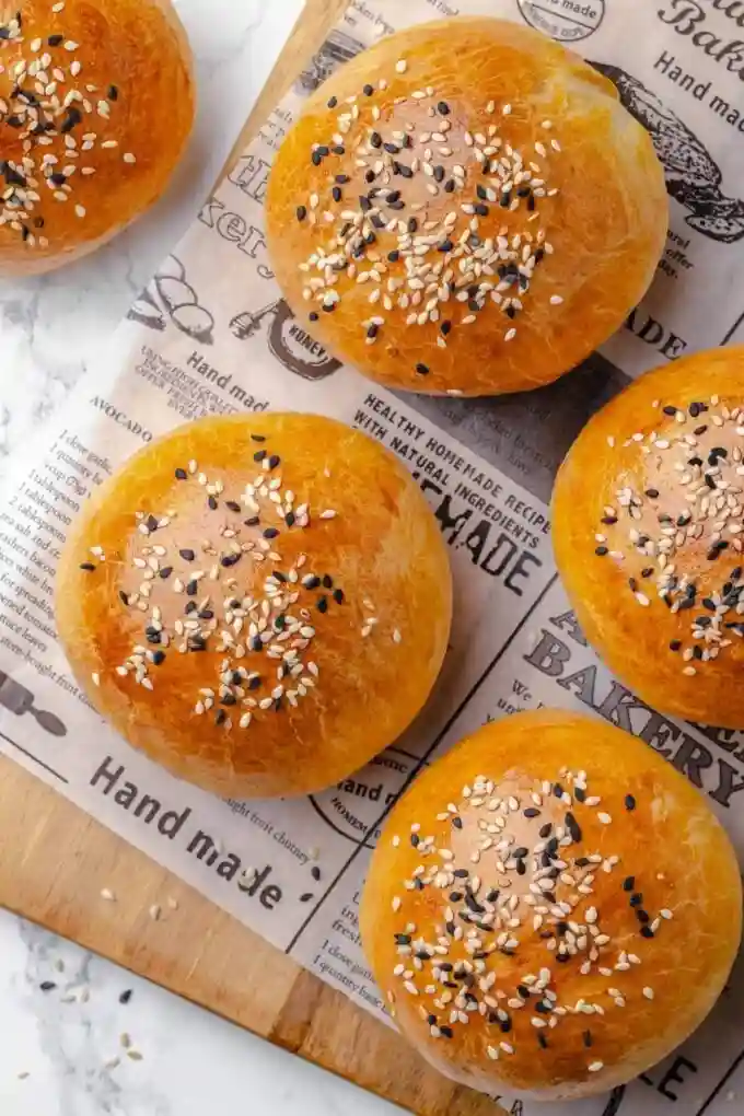 Frisch gebackene Brioche Brötchen mit Sesam auf Holzbrett serviert
