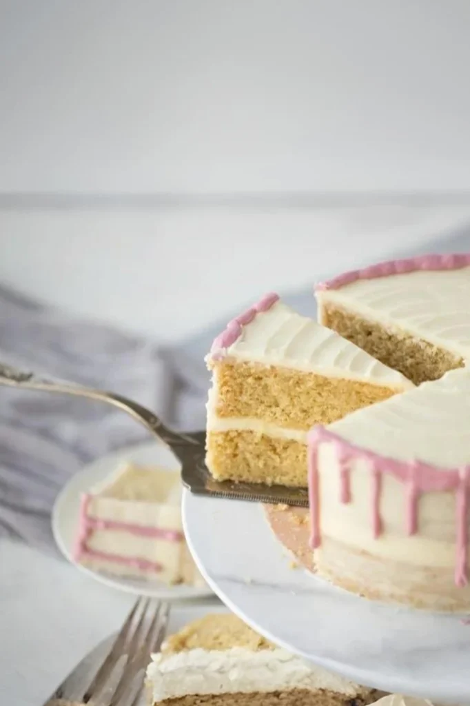Saftige glutenfreie Torte mit Vanille, zweilagig, hell dekoriert und angeschnitten auf einer Tortenplatte