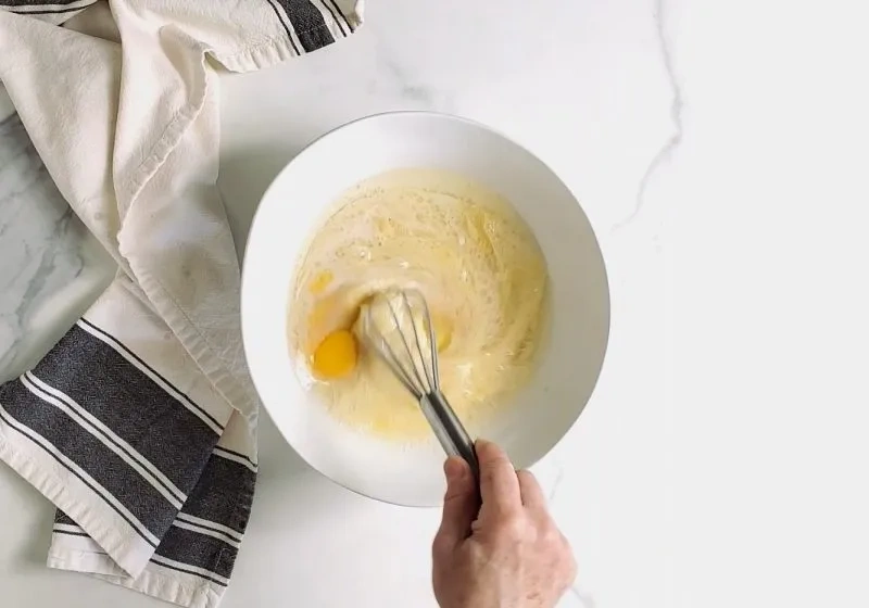 Flüssige Zutaten für glutenfreie Vanille-Torte werden mit einem Schneebesen verrührt